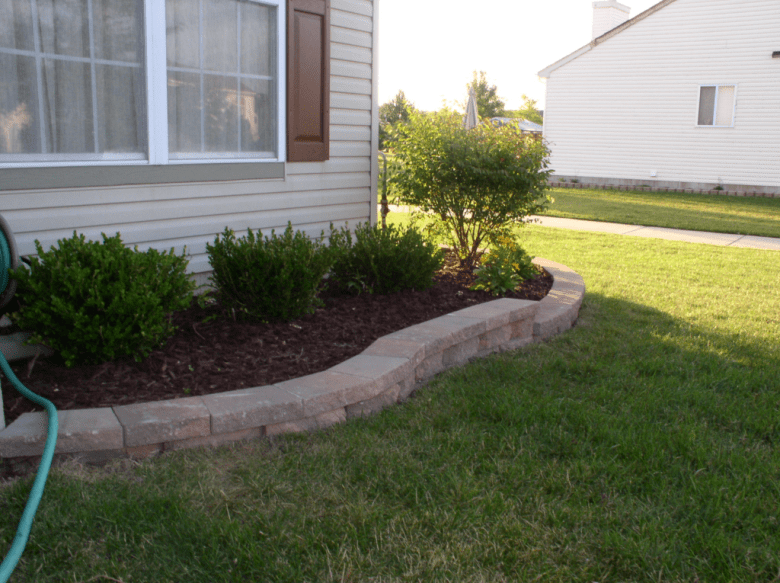 Brick edging garden bed corner along the side of a home