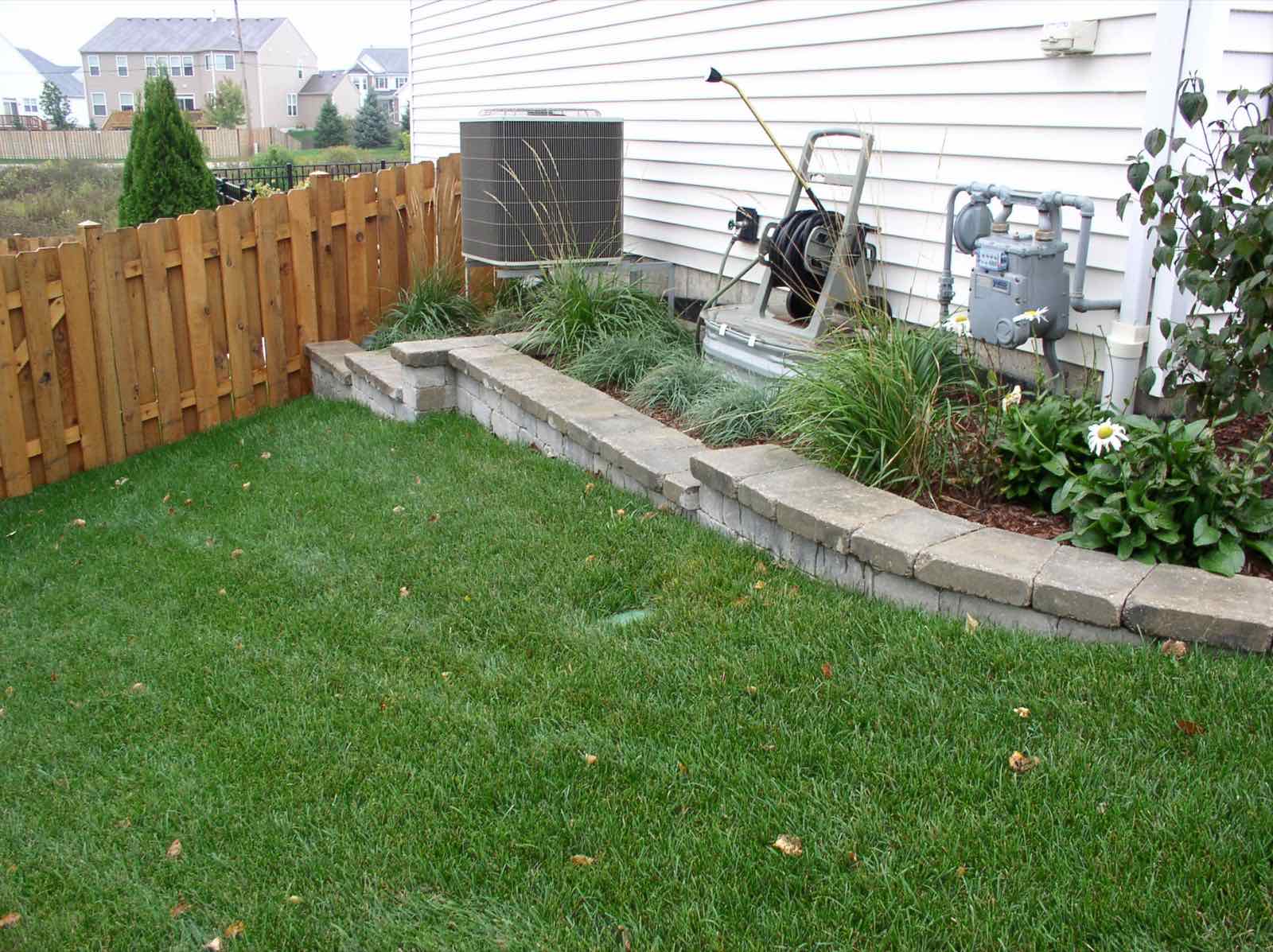 Brick edged garden bed along a backyard fence line