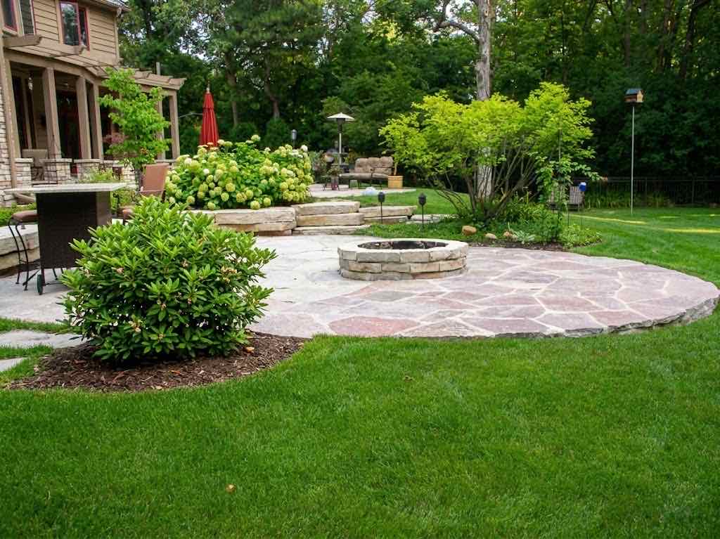 Stone fire pit on a flagstone patio surrounded by landscaping