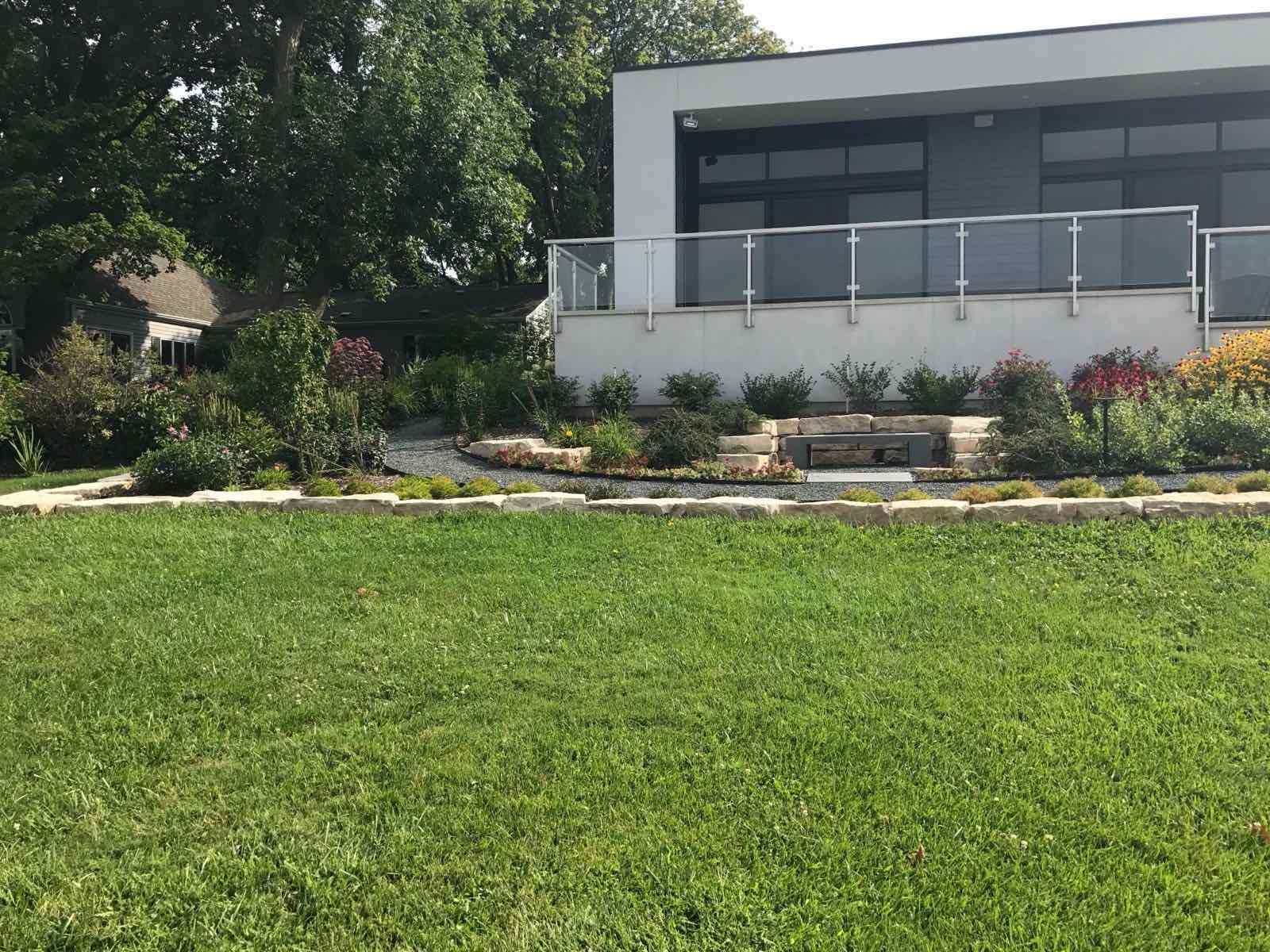 Modern landscape design with natural stone edging, a gravel path, and mixed perennial beds