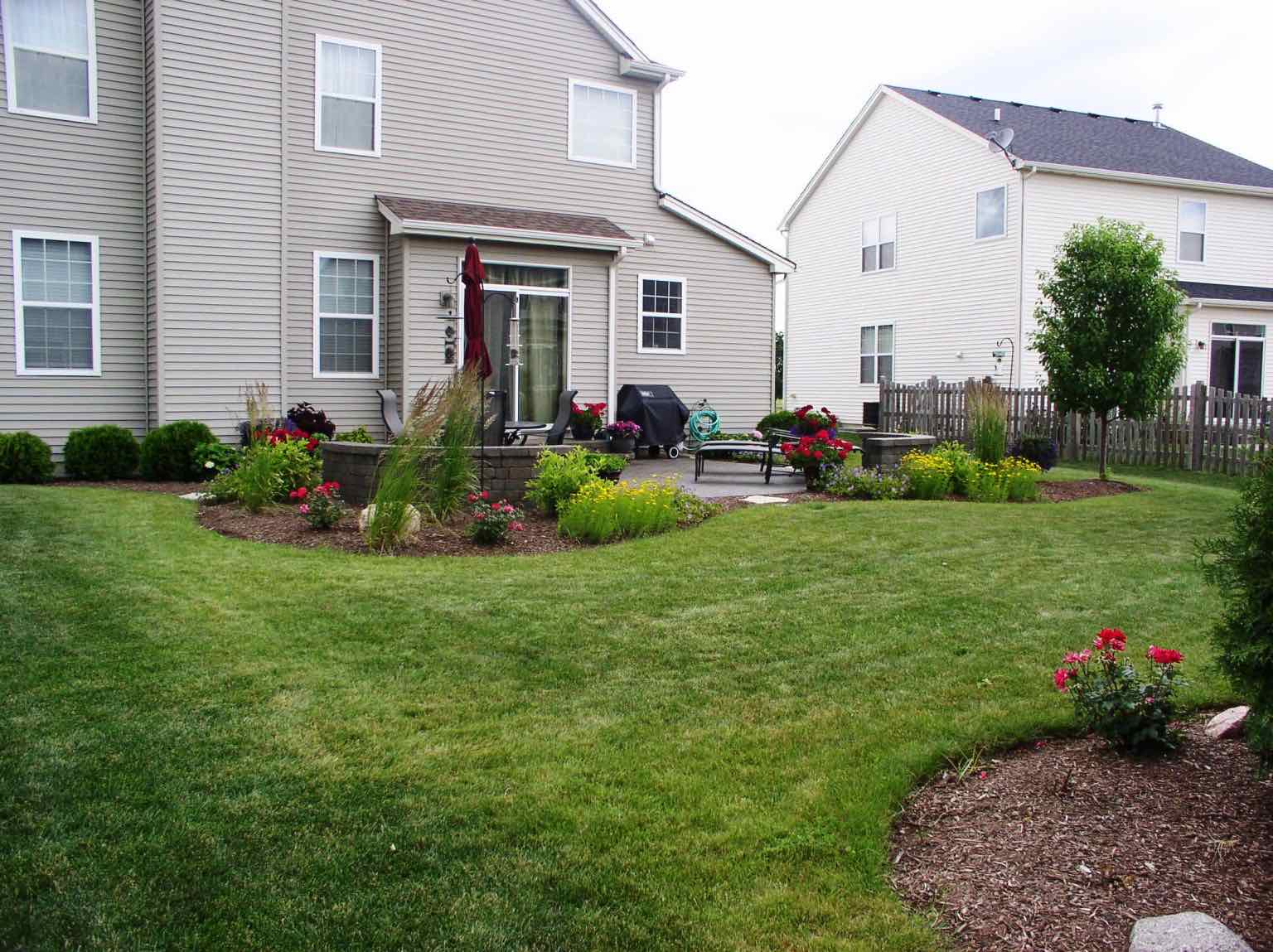 Backyard planting beds bordering a paver patio seating area