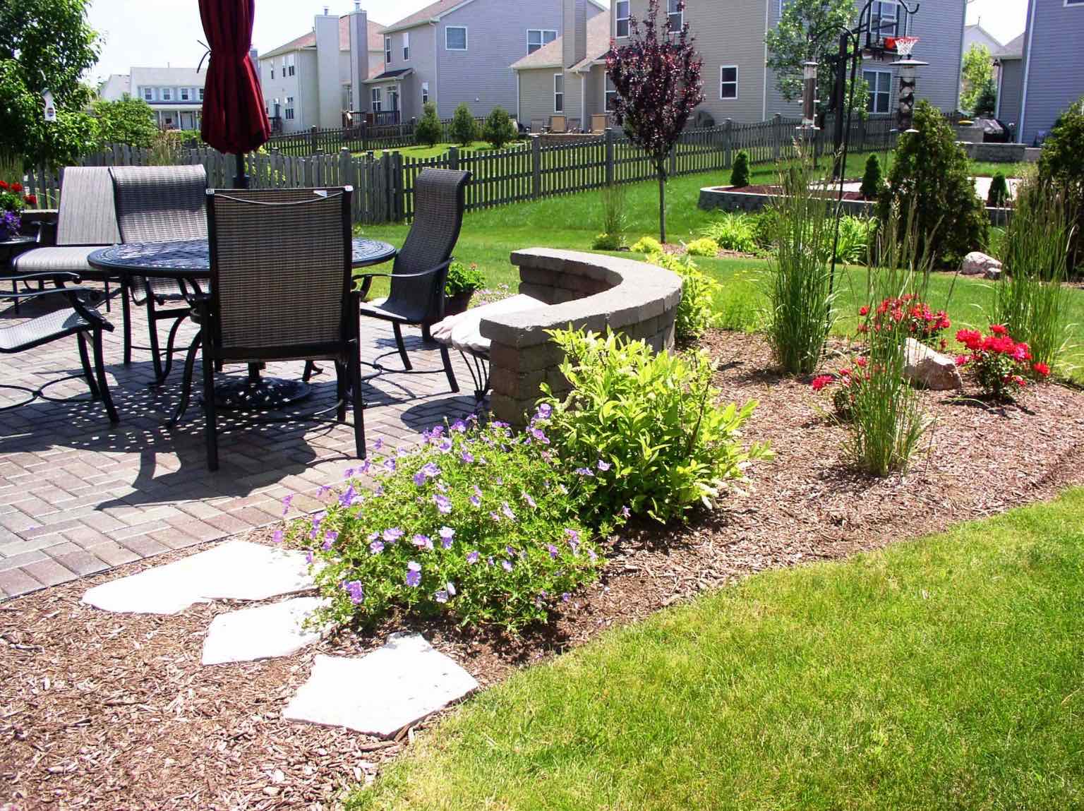 Backyard patio planting bed with ornamental grasses and roses