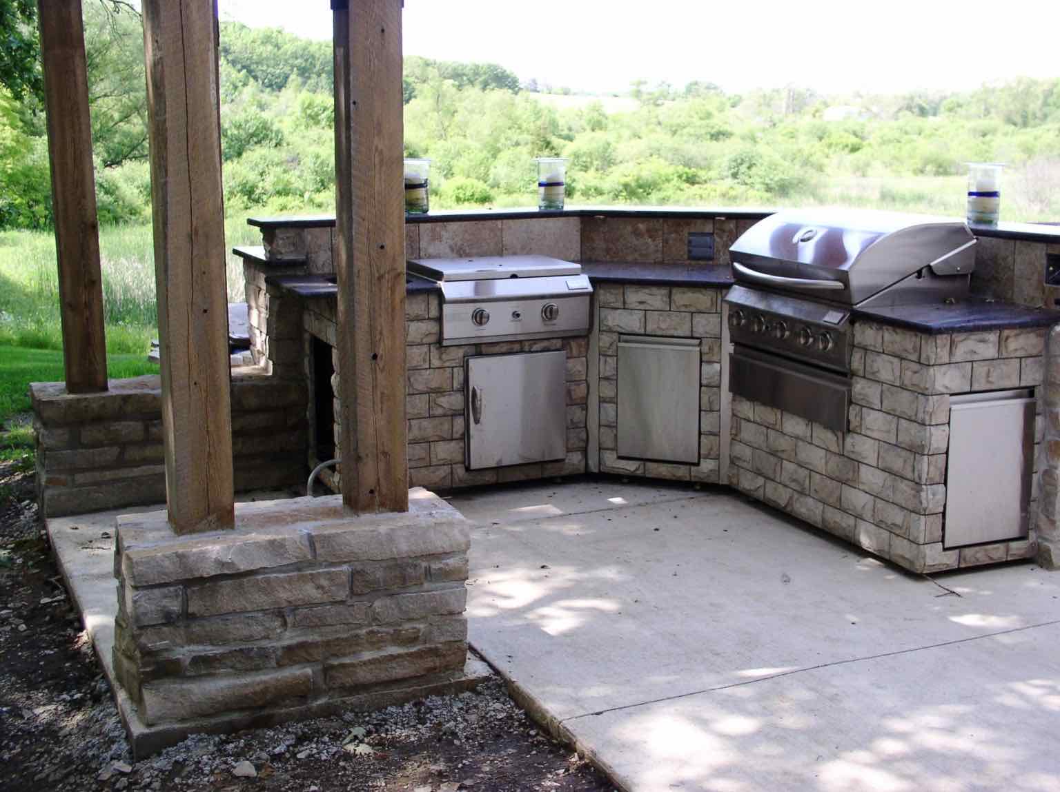 L-shaped stone outdoor kitchen with a built-in grill and refrigerator