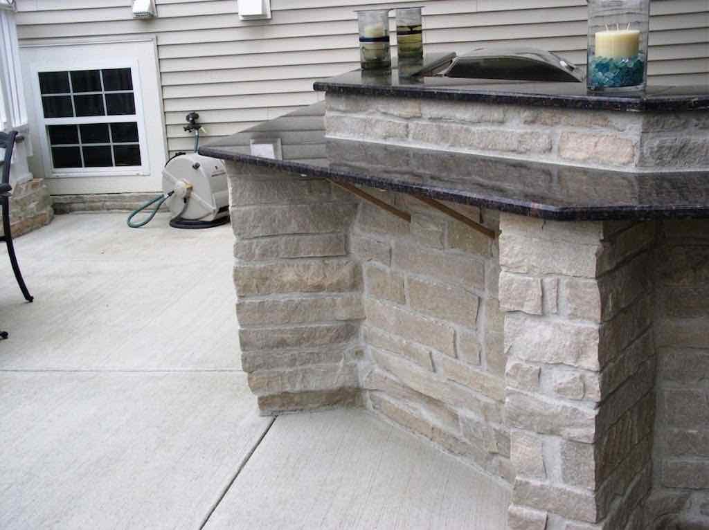 Close-up of a stone outdoor bar's granite countertop corner