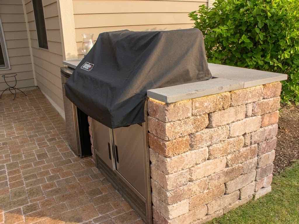 Built-in grill with a stone surround on a paver patio