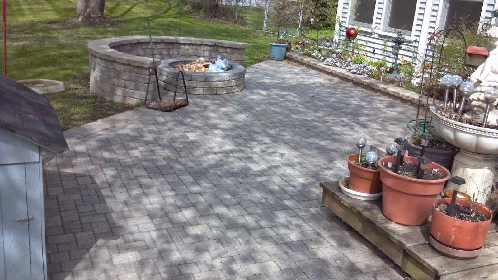 Paver patio with a round stone-walled fire pit lounge area