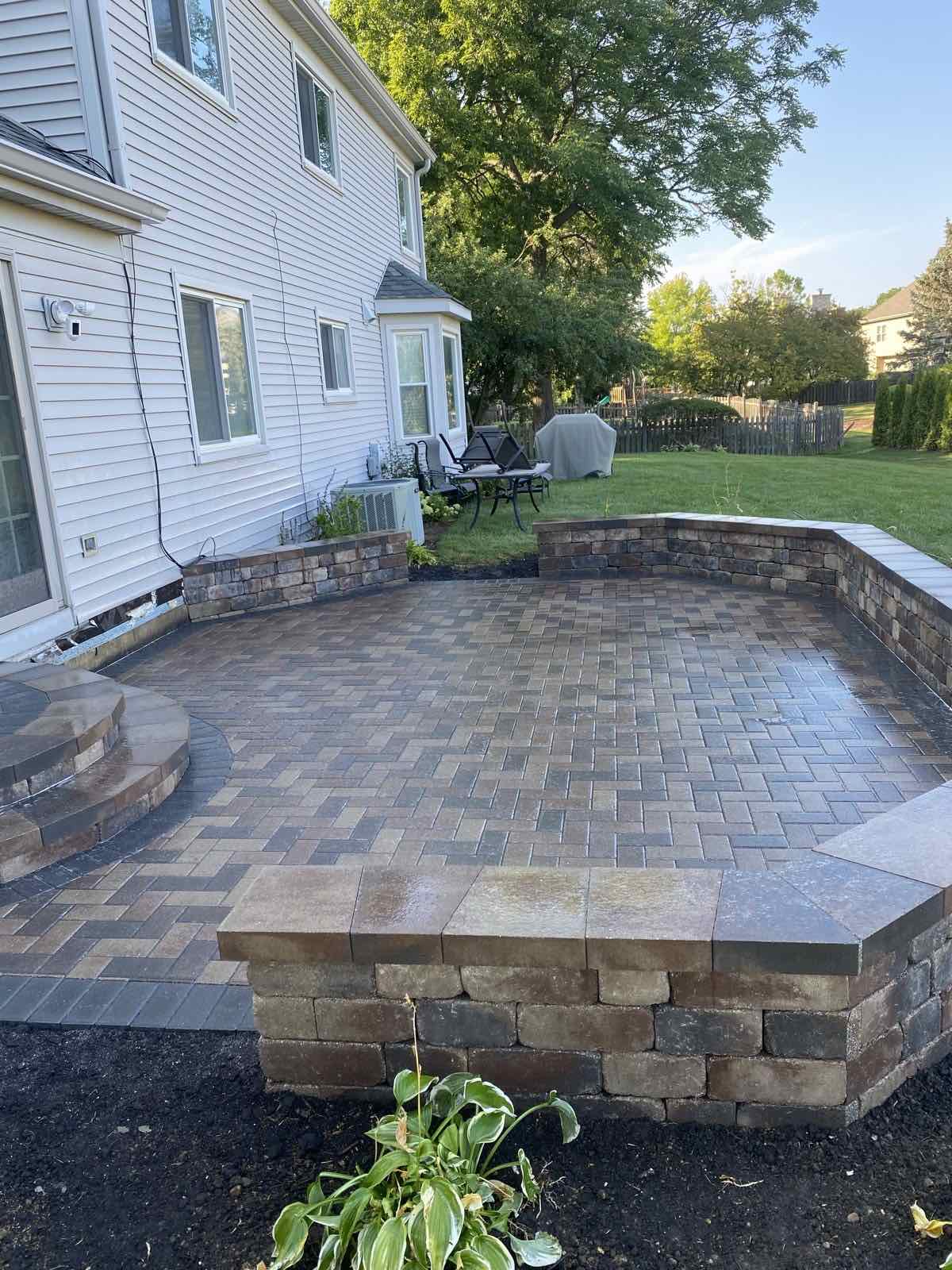 Basket-weave paver patio with a raised paver seat wall near a backyard deck