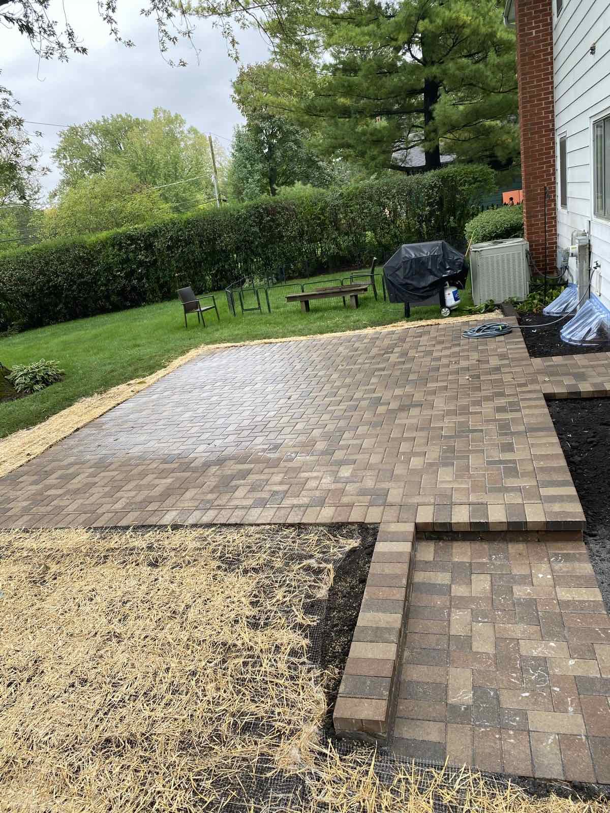 Freshly finished herringbone paver patio bordering a newly seeded lawn