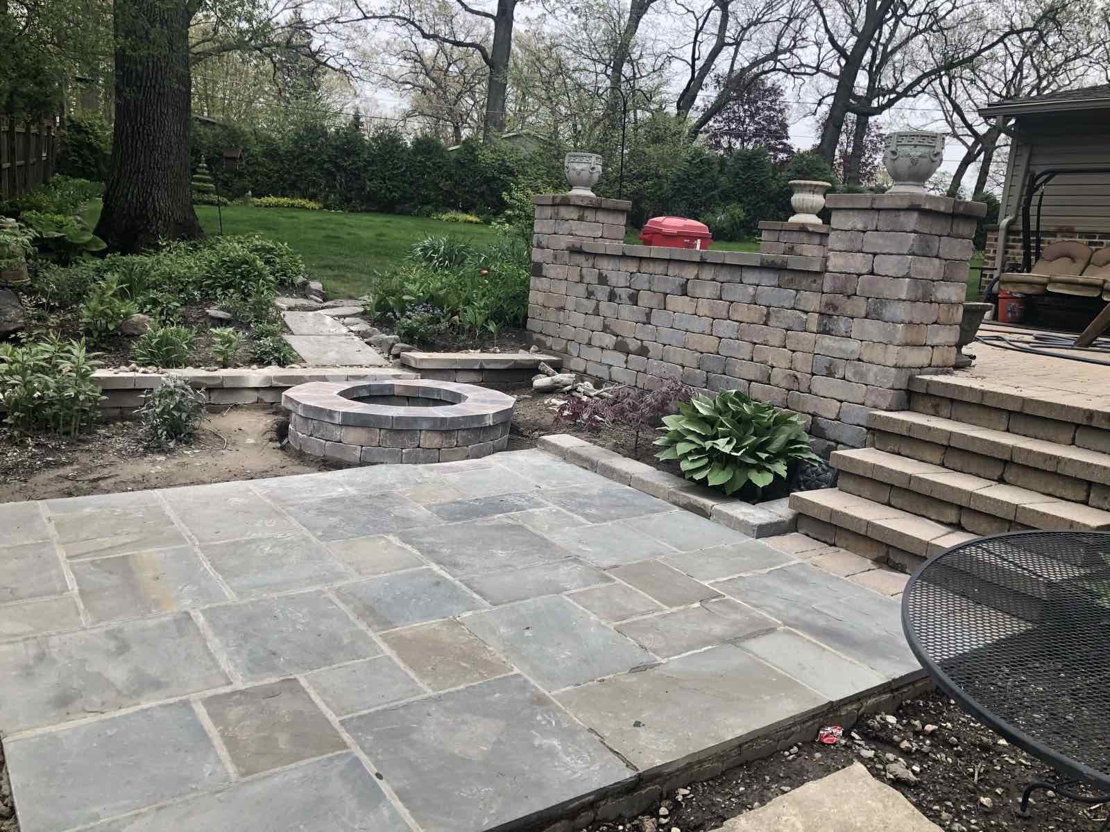 Bluestone patio with a paver fire pit, decorative wall, and steps to a deck