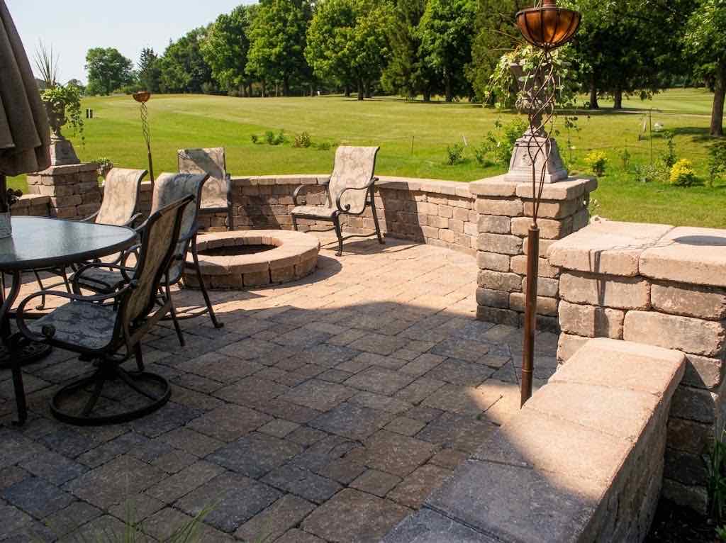 Paver patio with a fire pit and seat walls overlooking a golf course