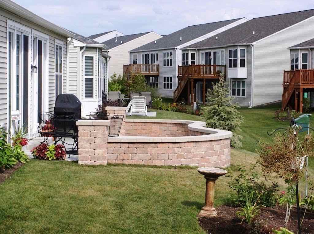 Curved stone seat wall enclosing a backyard patio