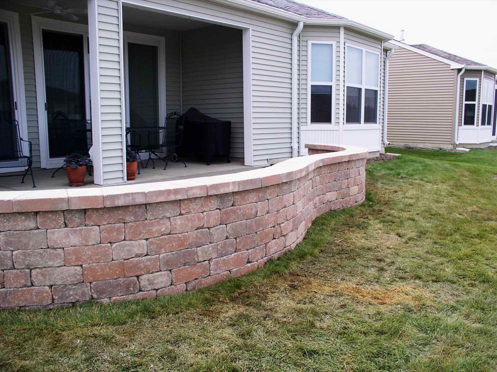 Curved stone retaining wall bordering a covered patio