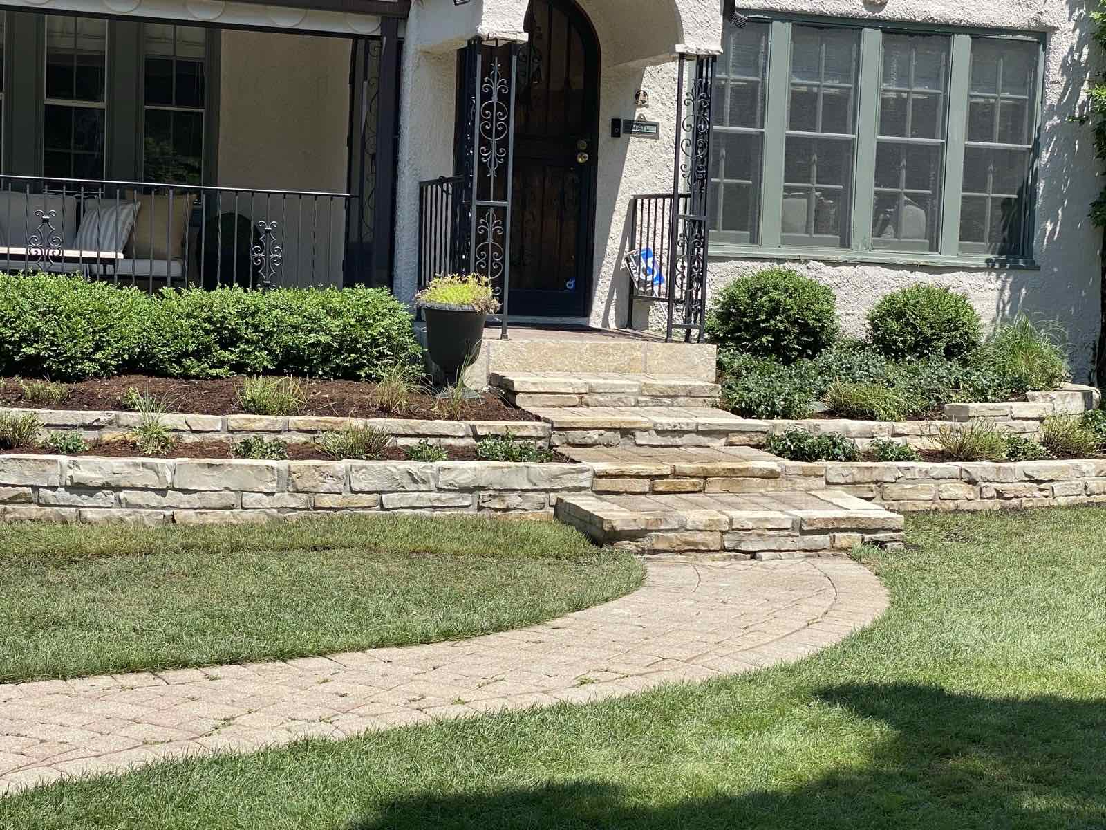 Curved natural stone retaining walls and steps leading to a front entrance