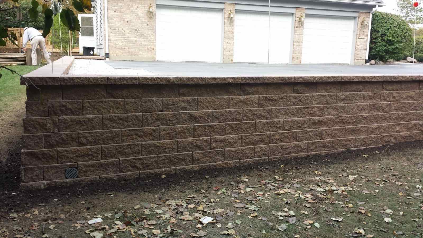 Large segmental block retaining wall raising a driveway to garage level