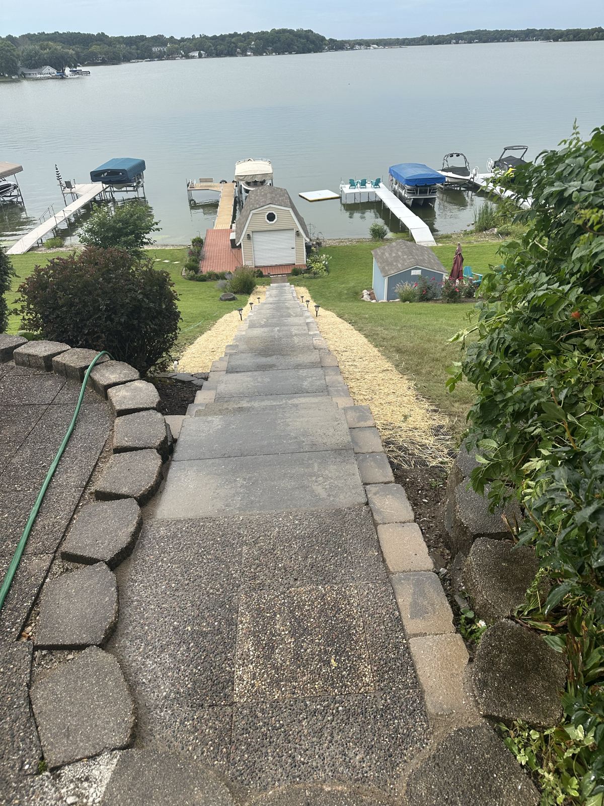 Paver block steps running down a sloped yard from the patio to a lakefront dock